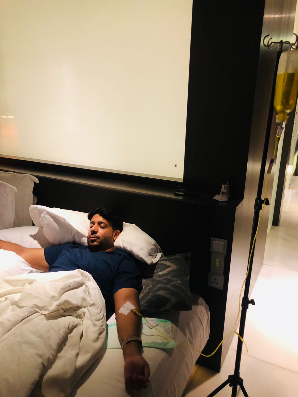 A man resting in bed receiving a mobile IV drip hydration treatment in a villa.